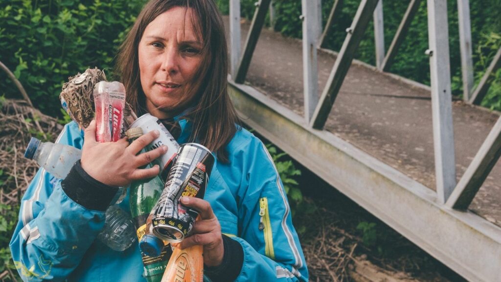 woman holding dirty cans and bottles that had been littered